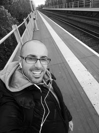 Portrait of smiling young man wearing headphones at platform
