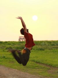 Blurred motion of man jumping over grassy field against sky