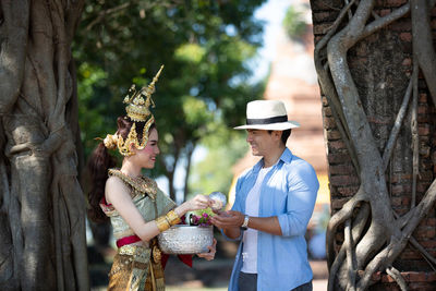 Statue of man holding woman standing by tree