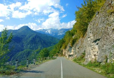 Road leading towards mountains against sky