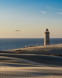 Scenic view of sea and lighthouse against sky during sunset