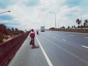 Rear view of man riding motorcycle on road