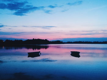 Boats in calm lake at sunset