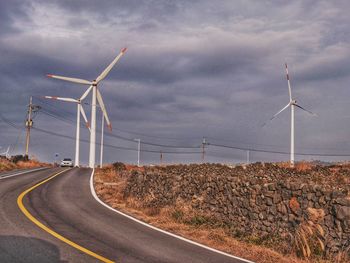 Wind turbines on road against sky