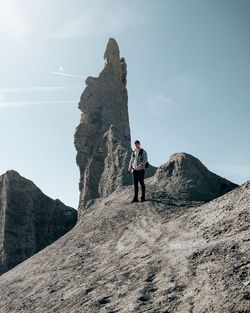 Man standing on rock by mountain against sky