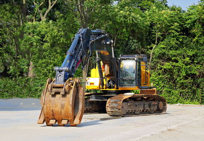 Construction site by road against trees