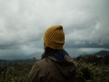 Rear view of woman standing on field against sky