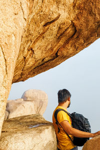 Rear view of man on rock against sky
