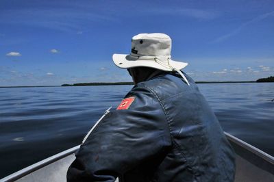 Man on boat in sea against blue sky during sunny day