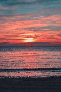 Scenic view of sea against dramatic sky during sunset