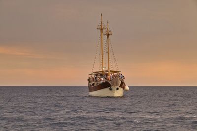 Ship in sea against sunset sky