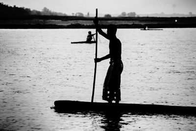 Side view of silhouette man standing in sea against sky