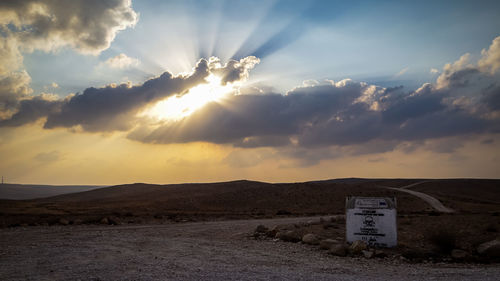 Information sign on field against sky during sunset