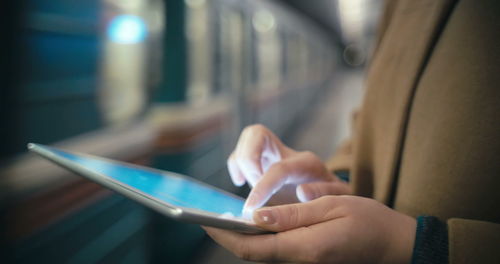 Midsection of person using mobile phone in bus