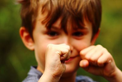 Close-up portrait of cute boy showing fists