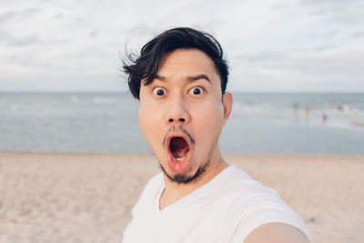 Portrait of mature man at beach against sky