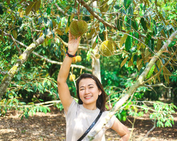 Portrait of young woman standing under fruit tree