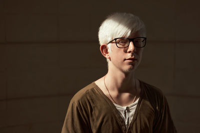 Portrait of young man wearing eyeglasses against black background