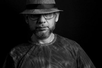 Black and white portrait of a man wearing a hat and glasses. isolated on black background.