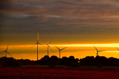 Silhouette windmill on field against sky during sunset