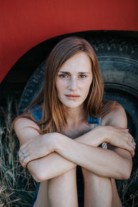 Portrait of young woman sitting against tire