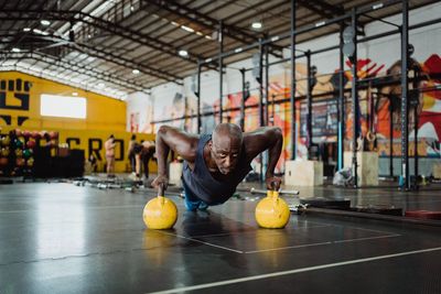 Man exercising with kettlebells on floor