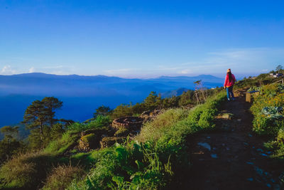 Rear view of man standing on mountain against sky