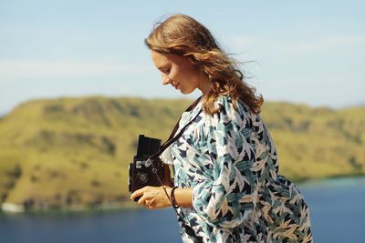 Midsection of woman photographing against sky