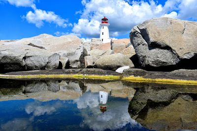 View of lighthouse by sea against blue sky