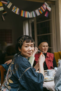 Side view portrait of transwoman sitting with friends during party in back yard