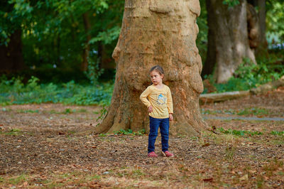 Cute young girl in front of a huge tree trunk at a botanical garden
