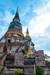 Low angle view of buddha statue by pagoda against sky at ayuthaya province