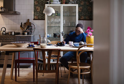 Teenage boy with head in hand studying at dining table