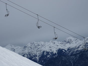 Overhead cable car over snow covered mountains against sky