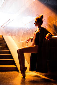 Side view of young woman sitting on staircase
