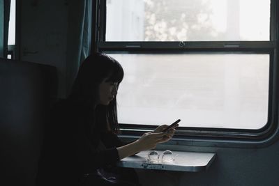 Young woman using mobile phone in train