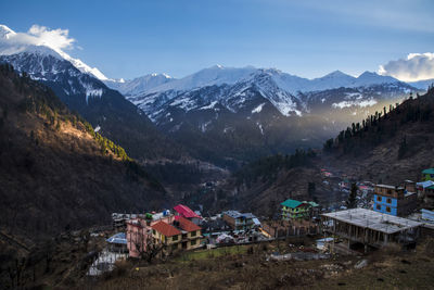 Houses by snowcapped mountains against sky