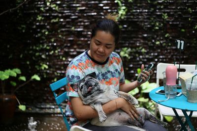 Smiling woman sitting with dog outdoors