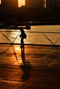 Silhouette woman walking against calm river