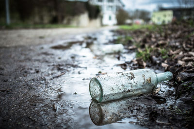 Abandoned bottle on puddle