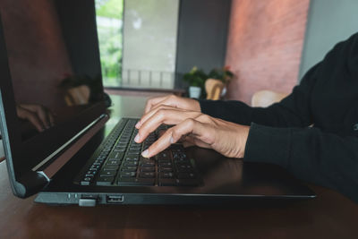 Midsection of man using laptop on table