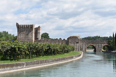 Arch bridge over river against buildings