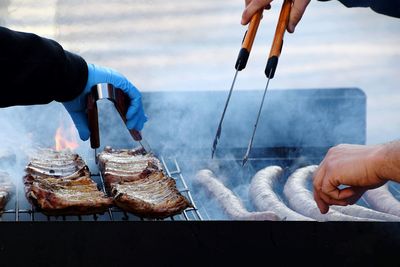 Low section of man holding fish on barbecue grill