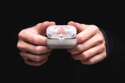 Midsection of man holding piggy bank against black background