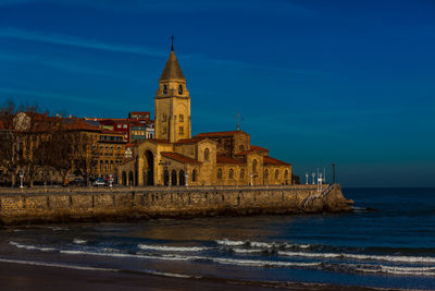 View of building by sea against blue sky