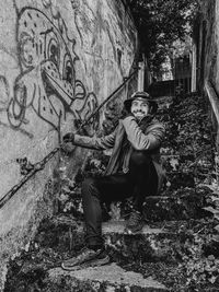 Portrait of smiling man sitting on steps by graffiti wall