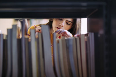 Woman searching books on shelf at library