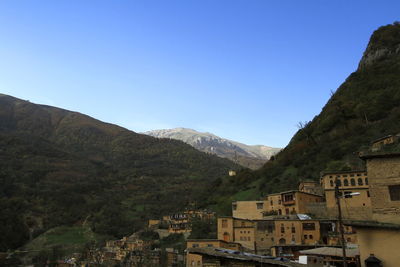 Scenic view of buildings and mountains against clear sky