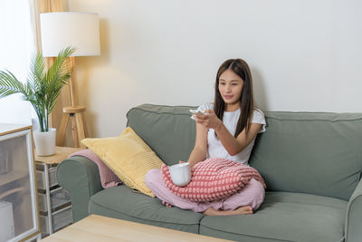 Portrait of young woman sitting on sofa at home