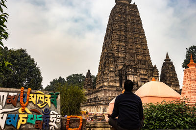 Rear view of man sitting against temple